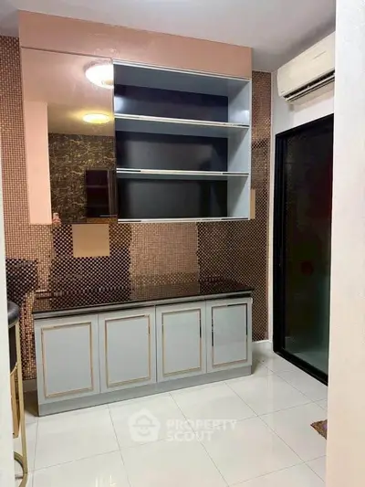 Modern kitchen with sleek cabinetry and air conditioning, featuring a stylish backsplash and glossy floor tiles.