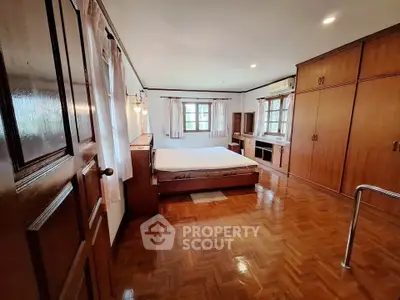 Spacious bedroom with wooden flooring and built-in wardrobes