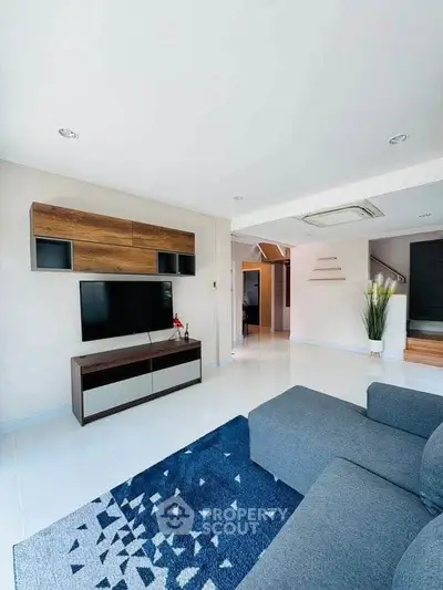 Modern living room with sleek furniture and stylish decor, featuring a cozy sofa and wall-mounted TV unit.