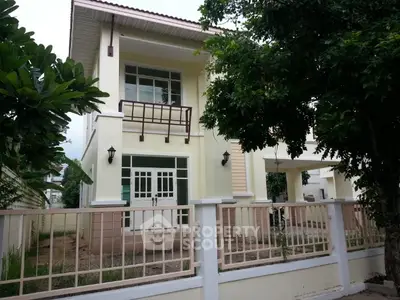 Charming two-story house with balcony and lush greenery in a serene neighborhood.