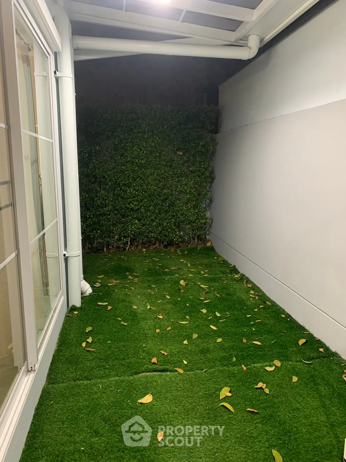 Charming small garden area with artificial grass and privacy hedge, perfect for relaxation.
