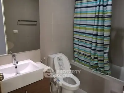 Modern bathroom with sleek fixtures and striped shower curtain in a contemporary apartment.