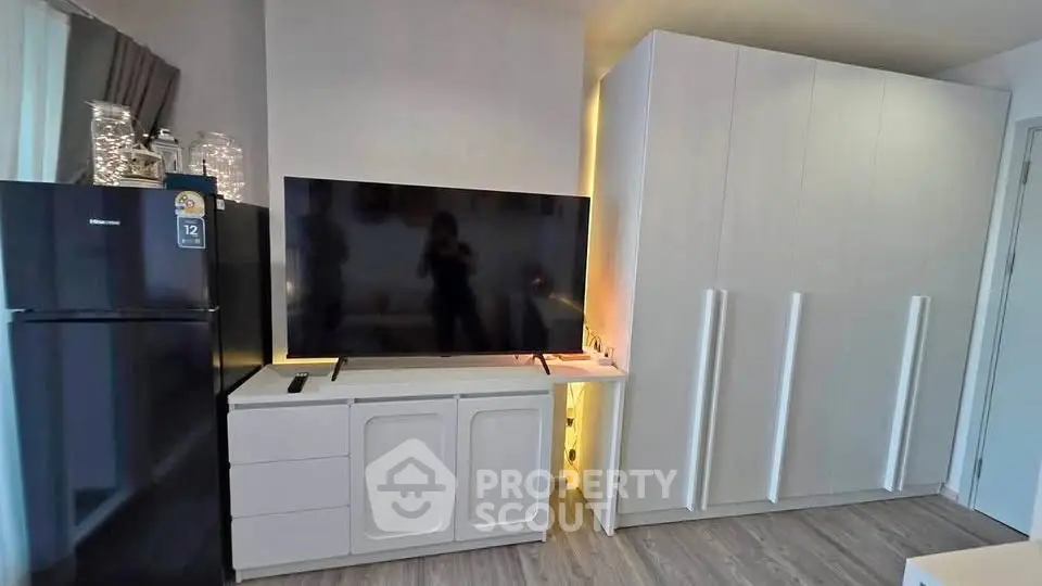 Modern living room with sleek TV setup and spacious storage cabinets.