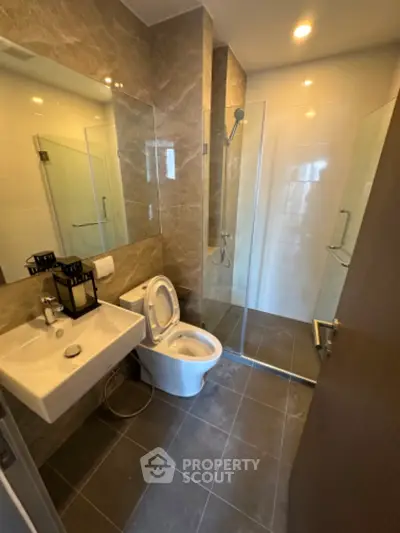 Modern bathroom with sleek design, featuring a glass shower enclosure and elegant fixtures.