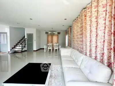 Spacious living room with elegant white sofa and floral curtains in modern home