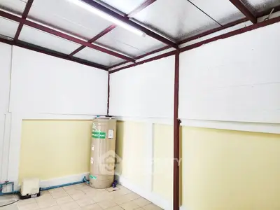 Spacious storage room with water heater and tiled floor in a well-lit area.