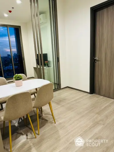 Modern dining area with stylish table and chairs, featuring large windows and elegant flooring.