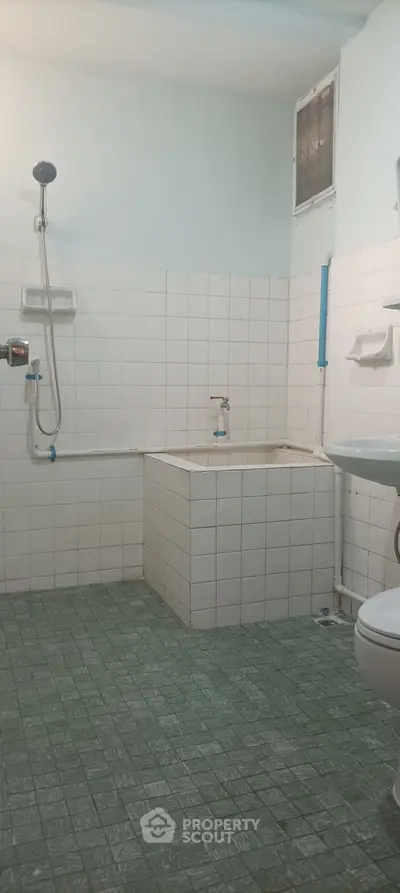 Spacious bathroom with tiled walls and floor, featuring a shower and sink.