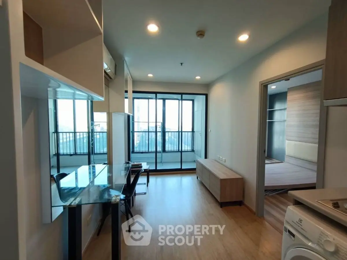 Modern apartment with open layout, glass balcony, and wooden flooring, featuring a washing machine.