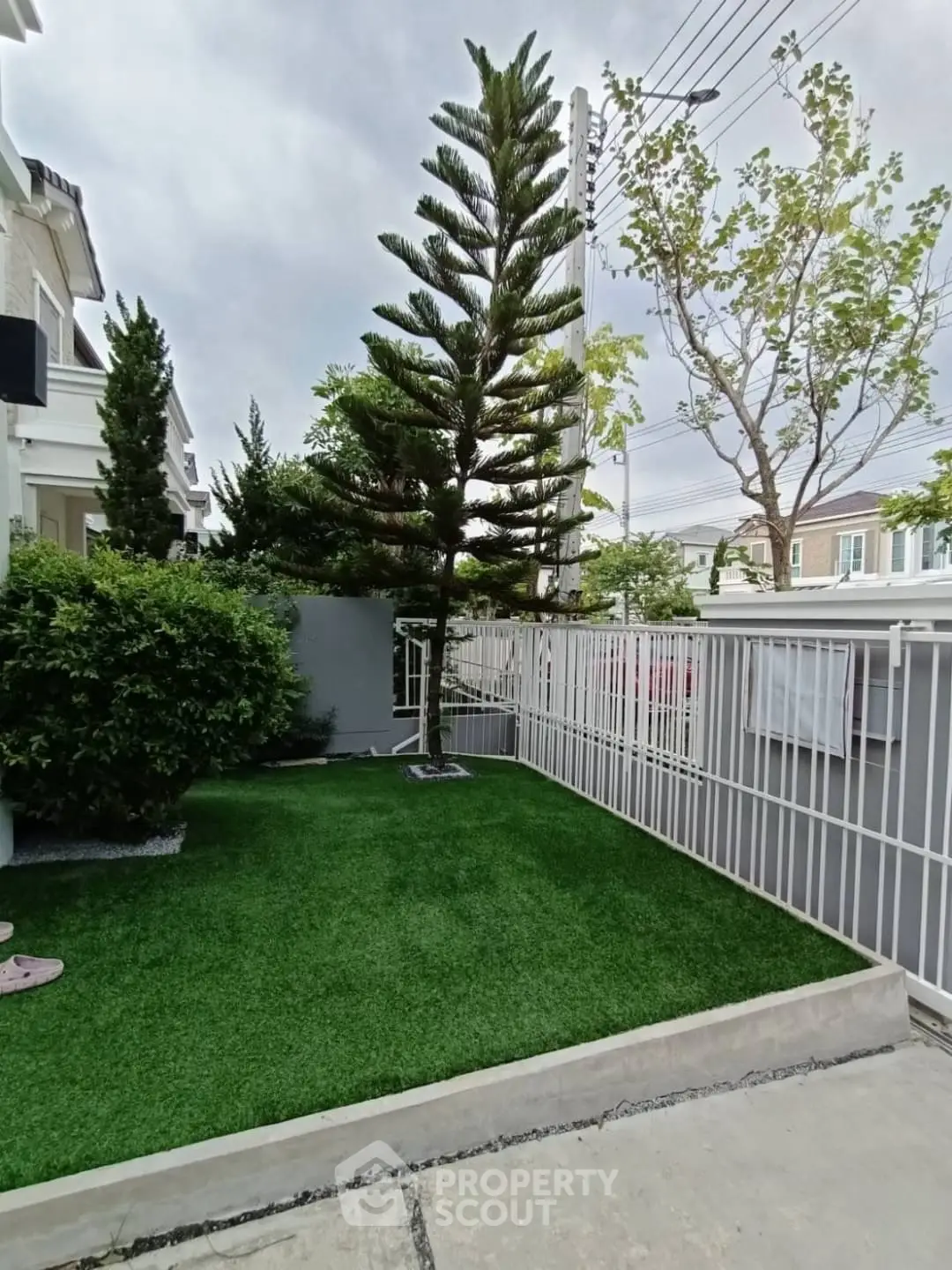 Charming garden area with lush greenery and modern fencing in a residential property.