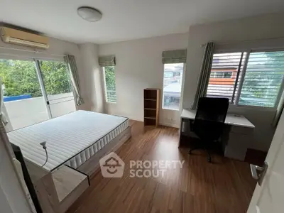 Spacious bedroom with large windows and natural light, featuring a desk and modern decor.