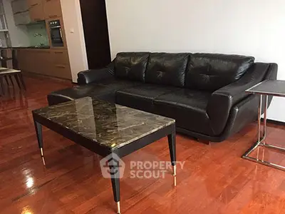 Modern living room with sleek black leather sofa and elegant marble coffee table.