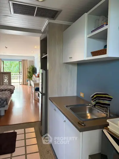 Modern studio apartment with compact kitchen and open layout, featuring a cozy bedroom and bright living area.