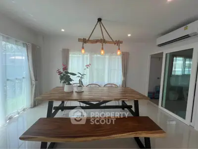 Modern dining area with wooden table and bench, stylish lighting, and large windows.
