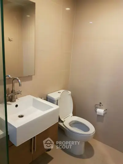 Modern bathroom with sleek fixtures and neutral tones, featuring a compact sink and toilet.
