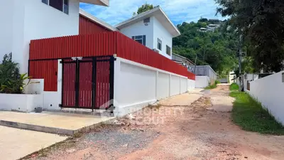 Modern white house with red fence and scenic hillside view