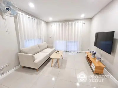 Modern living room with sleek furniture and wall-mounted TV, featuring bright lighting and elegant decor.