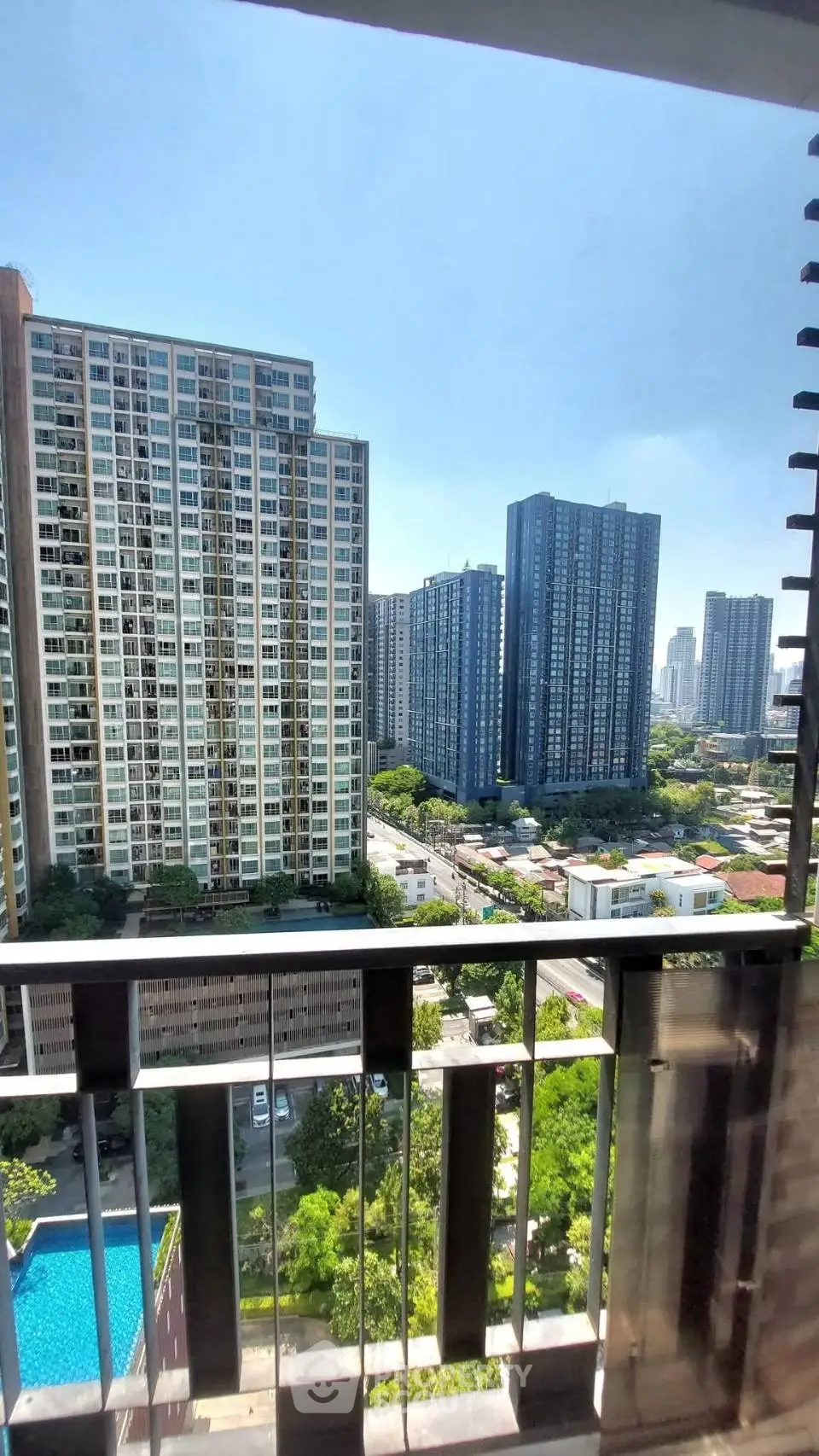 Stunning cityscape view from a high-rise balcony overlooking modern skyscrapers and lush greenery.