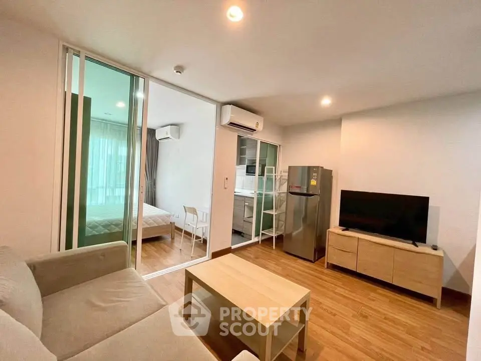 Modern open-plan living room with cozy sofa, TV, and kitchen area in a stylish apartment.