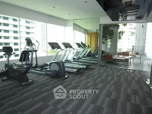 Modern gym with state-of-the-art equipment and floor-to-ceiling windows offering city views.