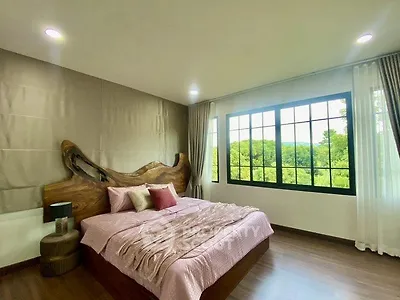 Spacious bedroom with large window offering scenic views and elegant wooden headboard.