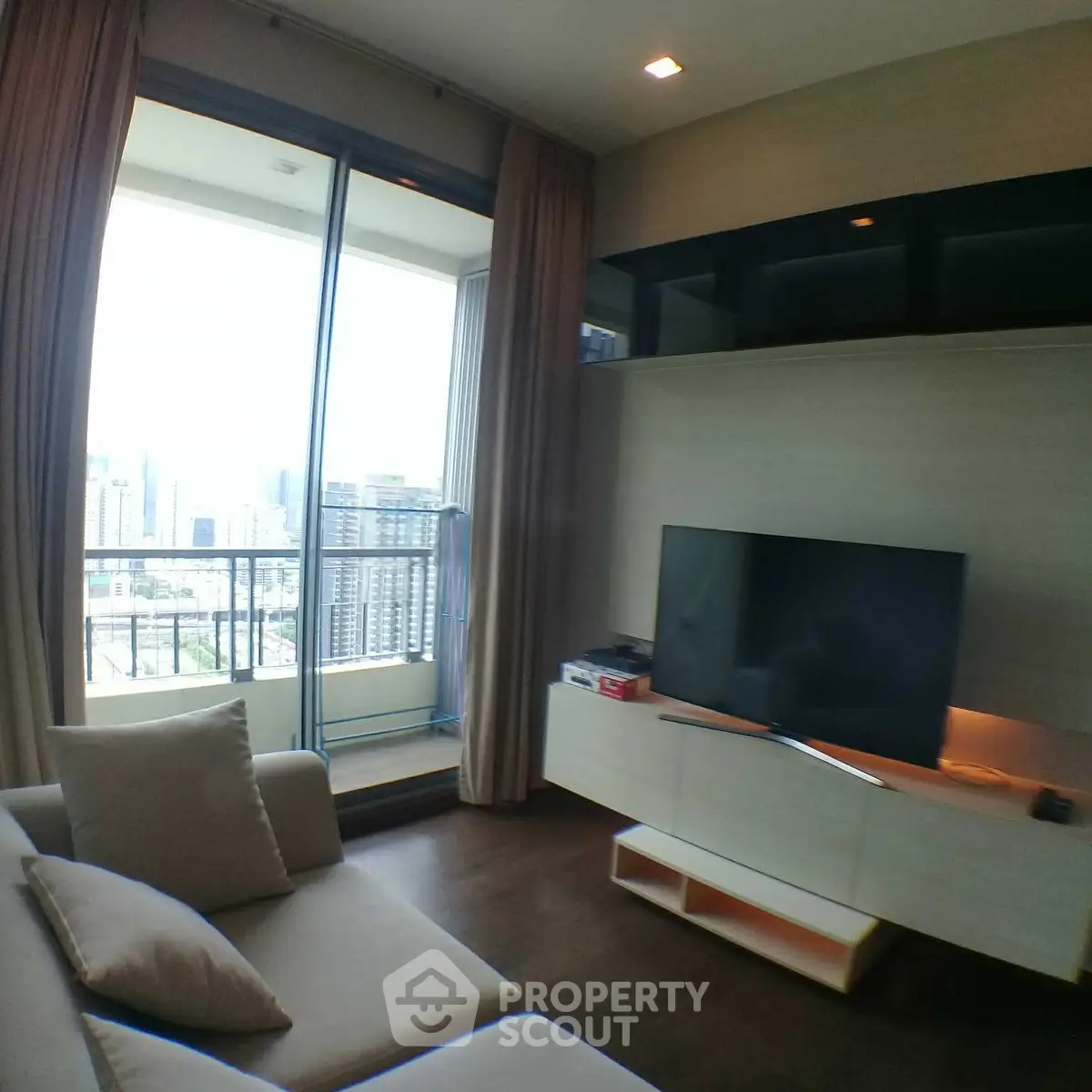 Modern living room with city view and balcony access, featuring sleek furniture and large TV.