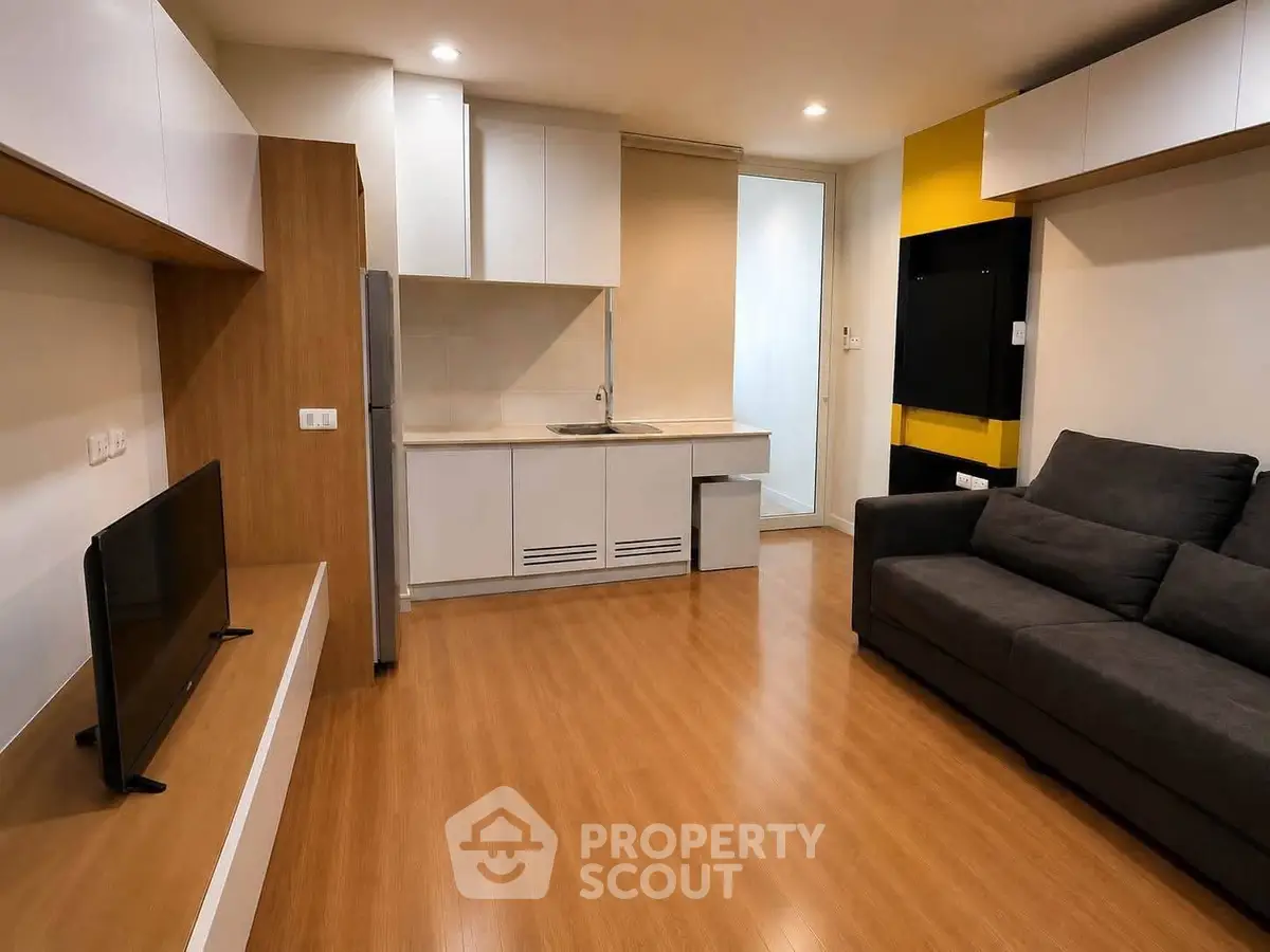 Modern living room with sleek kitchen and cozy sofa in open layout apartment.