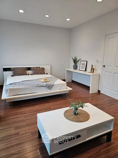 Modern bedroom with sleek furniture and wooden flooring, perfect for a cozy and stylish living space.