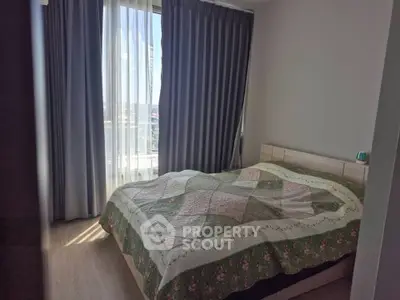 Cozy bedroom with large window and elegant curtains, featuring a comfortable bed with a stylish quilt.