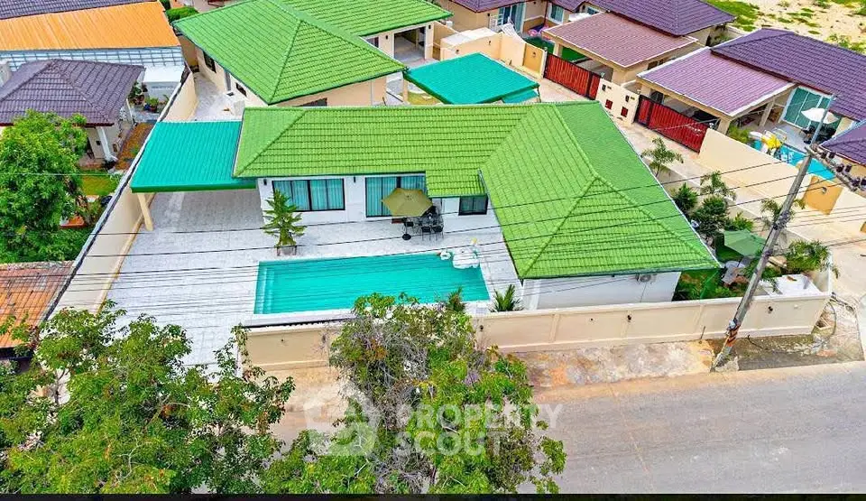 Stunning aerial view of modern villa with green roof and private pool in serene neighborhood.
