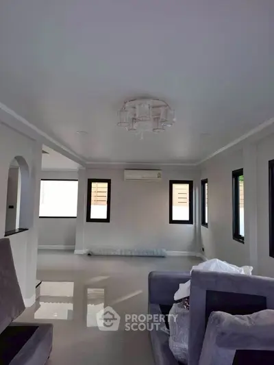 Spacious modern living room with sleek design and ample natural light, featuring stylish furniture and air conditioning.