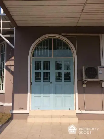 Charming entrance with arched doorway and air conditioning unit, perfect for modern homes.