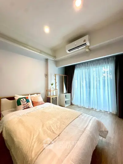 Bright and cozy bedroom with modern decor and large window for natural light.