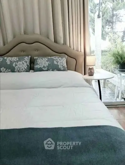 Cozy bedroom with elegant decor and large window overlooking a serene outdoor view.