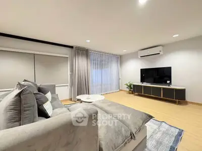 Spacious modern living room with plush gray sofa and sleek entertainment center.