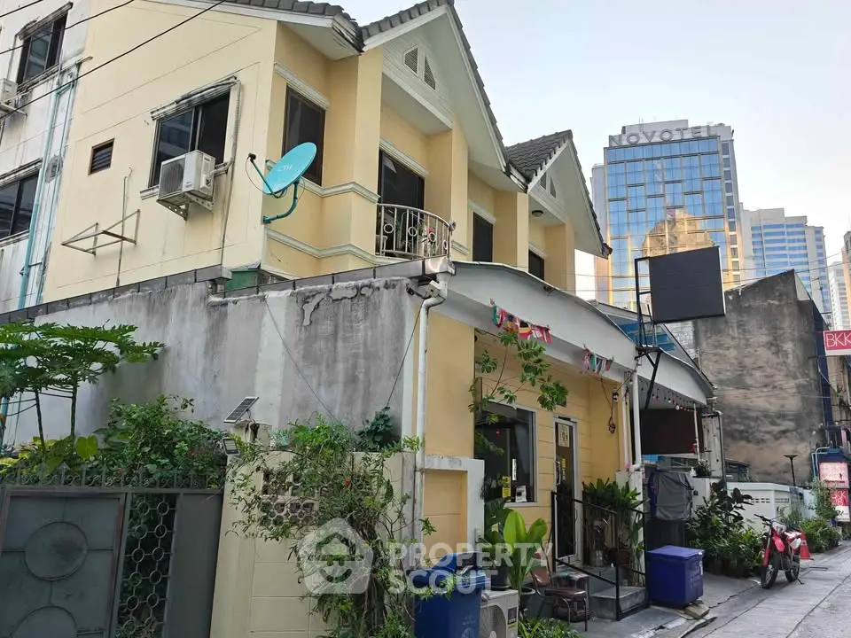 Charming urban house with lush greenery and city skyline backdrop, perfect blend of tranquility and convenience.