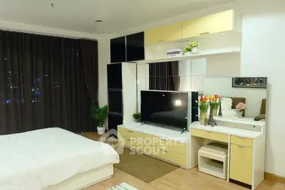 Modern bedroom with stylish furniture and large TV, featuring elegant decor and cozy ambiance.