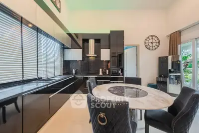 Luxurious modern kitchen with sleek black cabinets and elegant dining area.