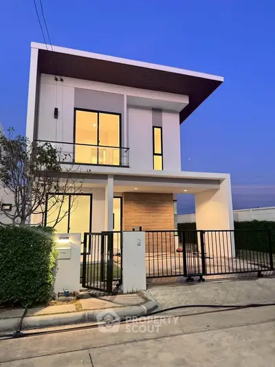 Modern two-story house with sleek design and large windows at dusk