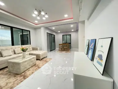 Spacious modern living room with elegant decor and open layout, featuring large windows and stylish furniture.