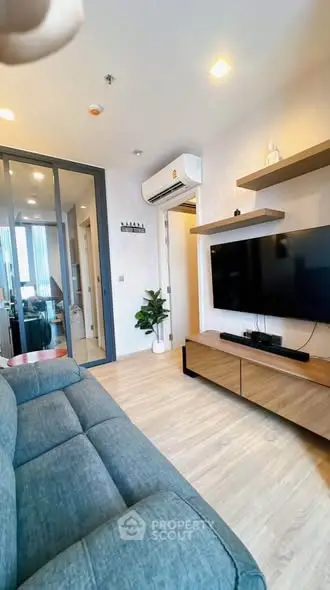 Modern living room with sleek furniture and wall-mounted TV in a cozy apartment.