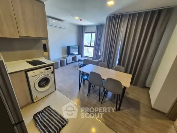 Modern open-plan living room with dining area and washing machine in stylish apartment.