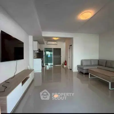 Spacious modern living room with sleek furniture and open kitchen layout, perfect for contemporary living.