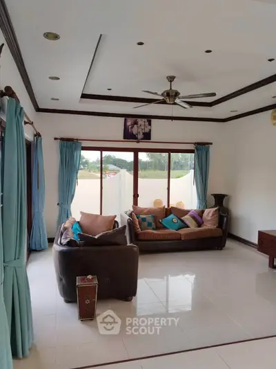 Spacious living room with elegant sofas and large windows offering natural light.