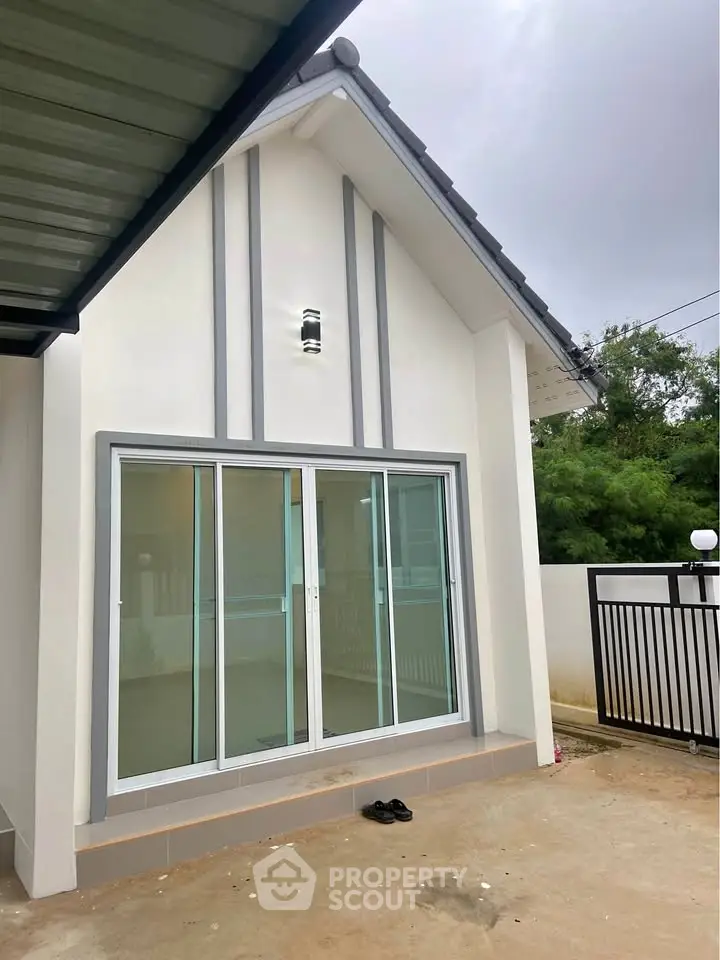 Modern minimalist house exterior with sliding glass doors and sleek design.