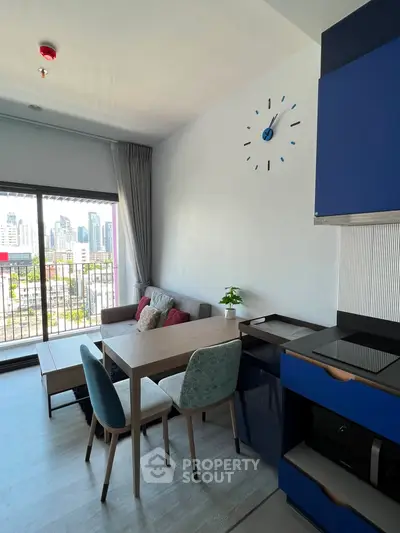 Modern living room with city view, stylish furniture, and open kitchen layout.