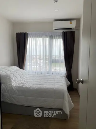 Cozy bedroom with large window and air conditioning unit, perfect for relaxation.