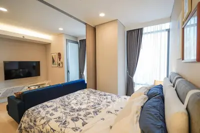 Modern bedroom with stylish decor and natural light, featuring a cozy bed and a sleek TV setup.