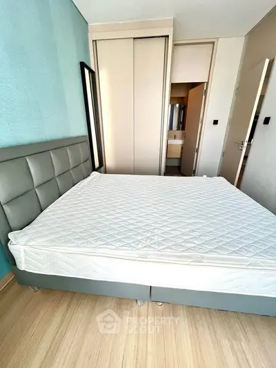 Spacious bedroom with modern design and ample natural light, featuring a comfortable bed and stylish decor.