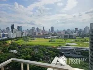 Stunning cityscape view from high-rise balcony overlooking lush green park and skyline.